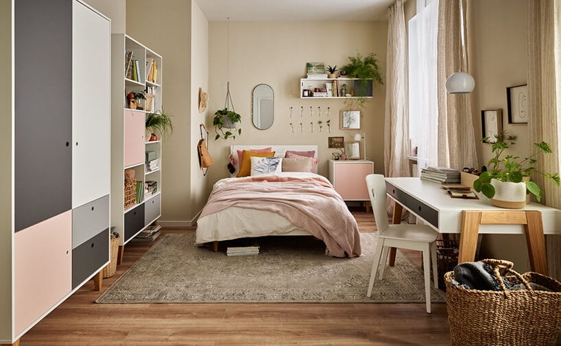 sypialnia z szafą w różowo szarych barwach oraz dużym łóżkiekiem z różową narzutą