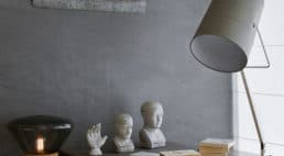 betonowa ściana z obrazem i statuetkami i lampką