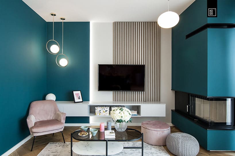 elegancki mały salon z kominkiem narożnym z jaskrawą niebieską ścianą z drewnianym parkietem