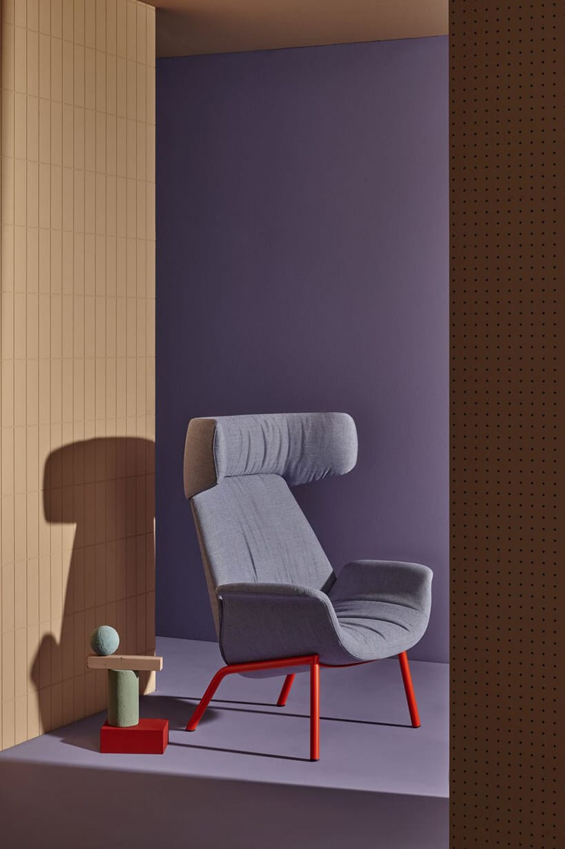 szary fotel z czerwoną ramą w przejściu z beżową oraz fioletową ścianą