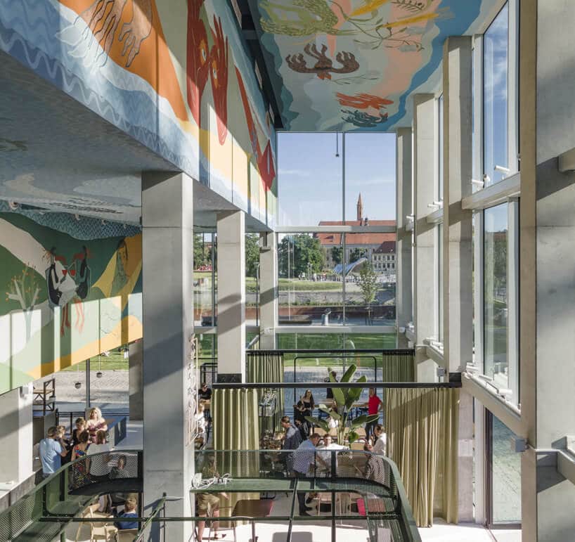 przestrzeń wspólna w Concordia Design na tle przeszklonych ścian i kolorowych rysunkach pod sufitem