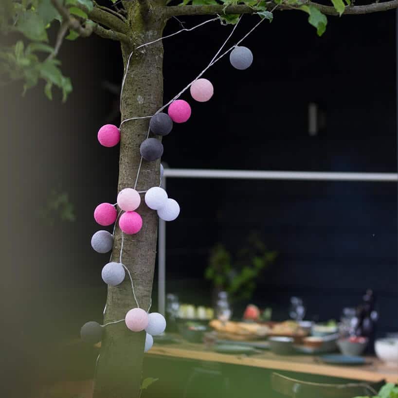sznur z oświetleniem cotton balls wokół drzewa w ogrodzie