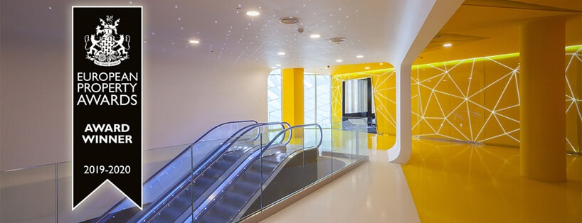 schody ruchome w Mori Cinema na tle żółtej ściany i sufitu z małymi światełkami