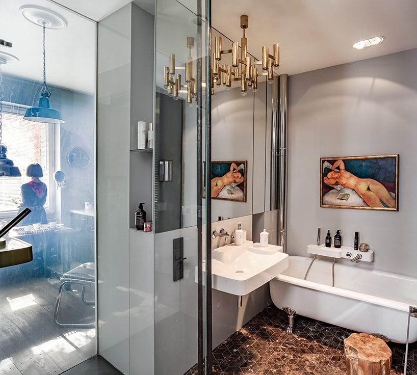łazienka z wanną na lwich chromowanych łapach przy wiszącej umywalce pod dużym lustrem w łazience ze złotawymi kaflami