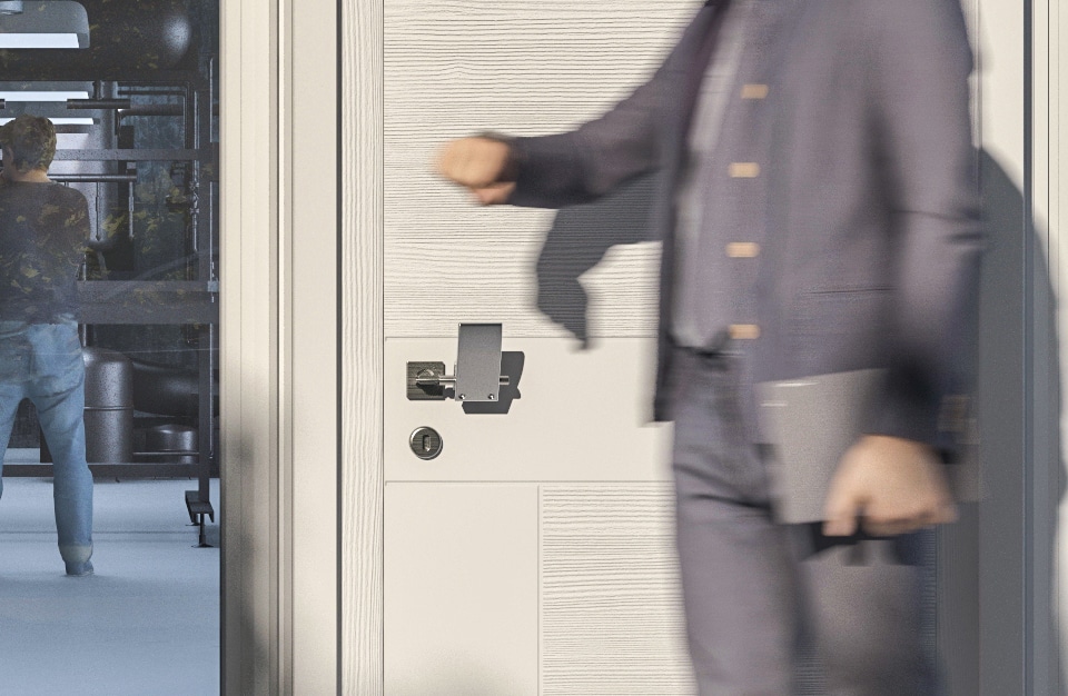 mężczyzna przy beżowych drzwiach z nakładką na klamkę od Gligo-Tech