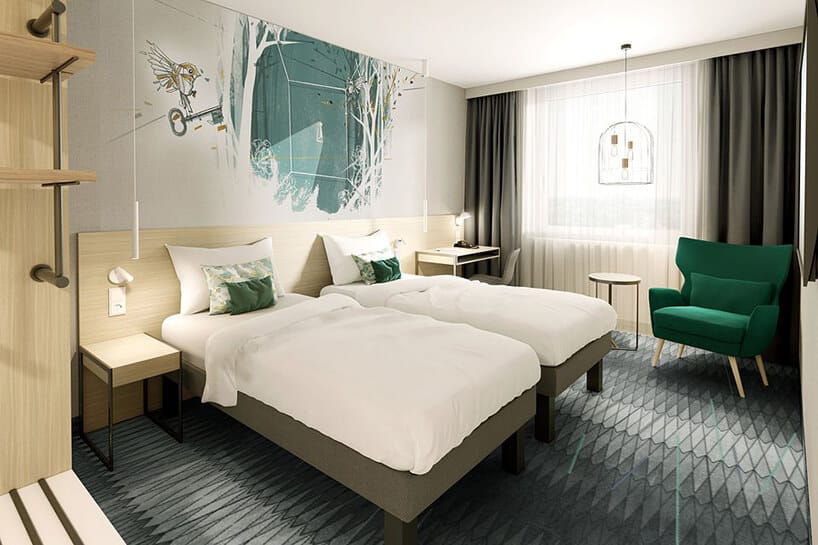 wnętrze hotelu ibis Styles Kraków od Accor jasne wnętrze w pokoju z dwoma łóżkami z zieloną grafiką na ścianie i zielonym fotelem