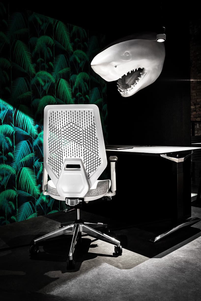 biały fotel obrotowy przy biurku na tle głowy rekina