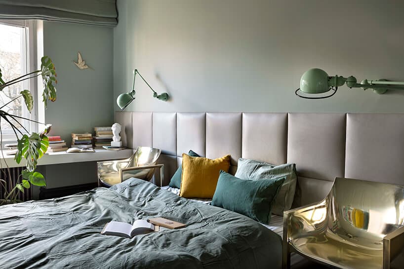 duża sypialnia z zieloną ścianą i częściowo obitą skórzanymi poduszkami jako tło dla dwóch błyszczących krzeseł