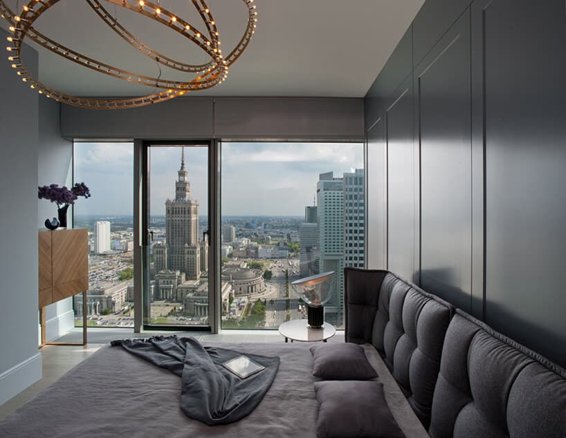 elegancka sypialnia z dużym łóżkiem na tle panoramicznego okna z widokiem na płac kultury