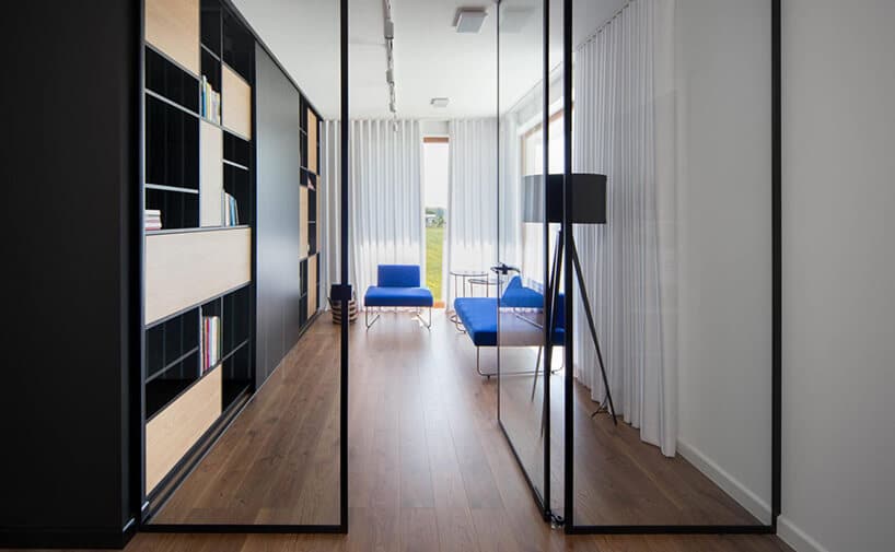 pokój z ciemną drewnianą podłogą z przeszkloną ścianą wejściową z niebieską sofą i fotelem