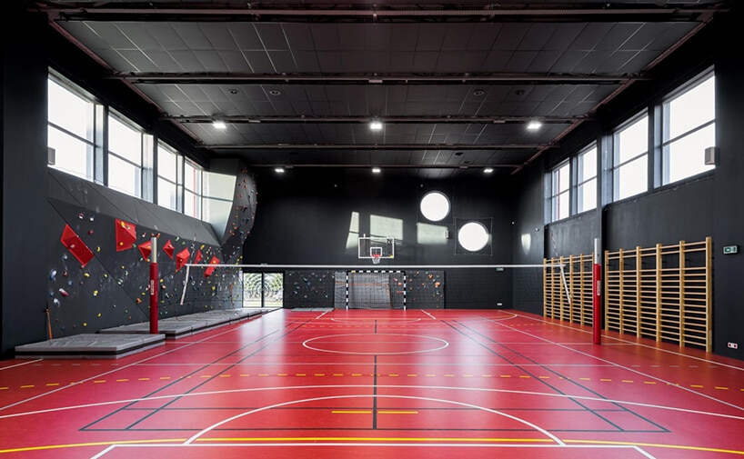 czarna sala gimnastyczna z czerwoną nawierzchnią na podłodze ze ścianką wspinaczkową