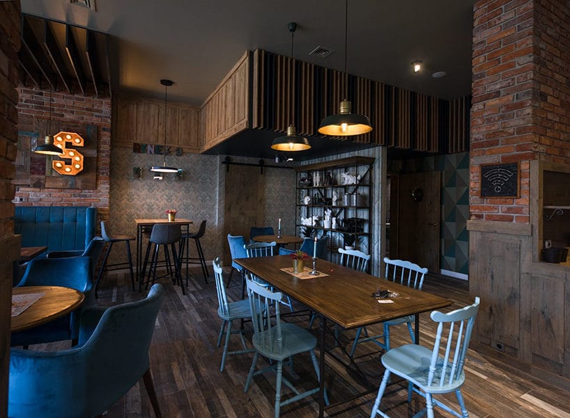 ciemne wnętrze restauracji z drewnianym wykończeniem ścian pod sufitem i wkomponowanymi cegłami