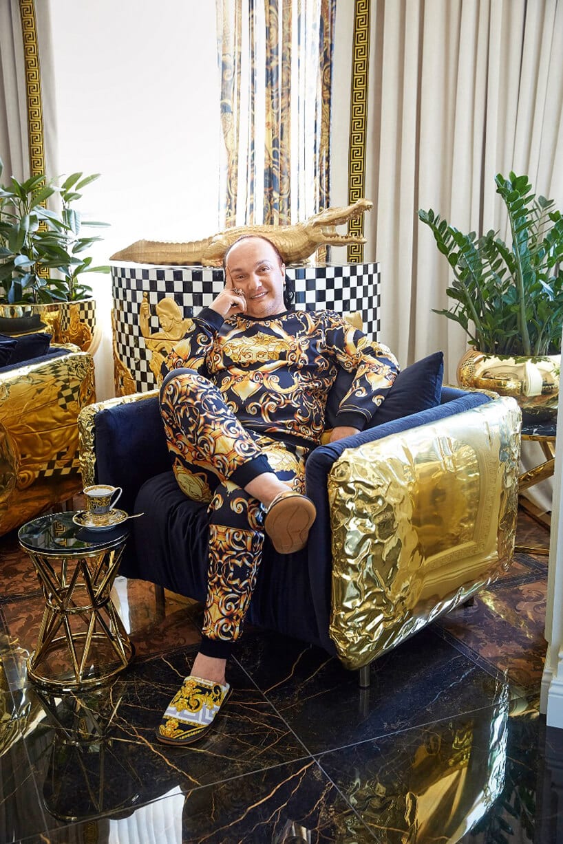 mężczyzna w zdobionej piżamie siedzący w niebieskim fotelu ze złotymi zdobieniami