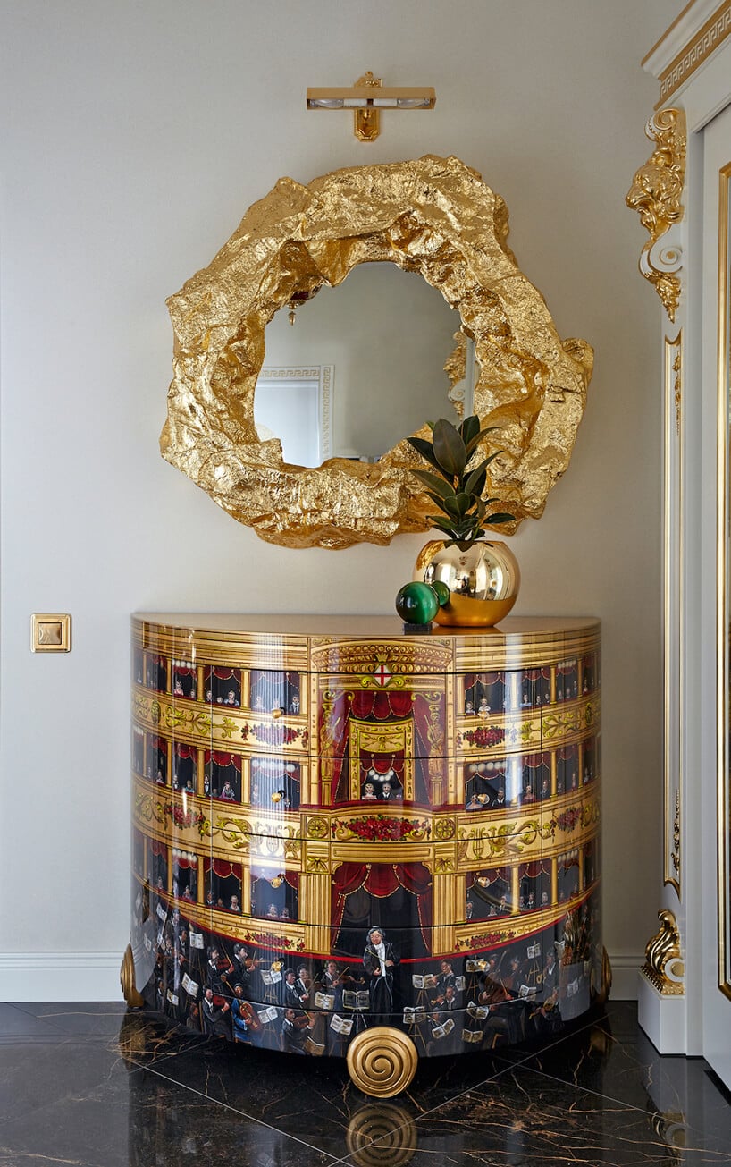 lustro z grubą złotą ramą nad stolikiem ze złotym malowaniem