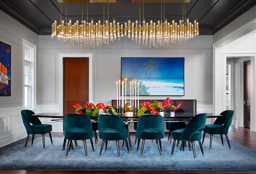 modernistyczne wnętrze Ravenswood Residence elegancka jadalnia z czarnym stołem niebieskim dywanem i dwoma złotymi żyrandolami