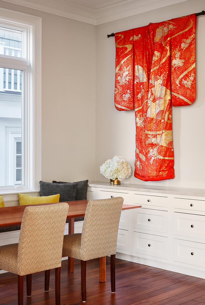 modernistyczne wnętrze Ravenswood Residence pomieszcze nie z drewnianym stołem długa białą szafką i pomarańczowym kimonem zawieszonym na ścianie