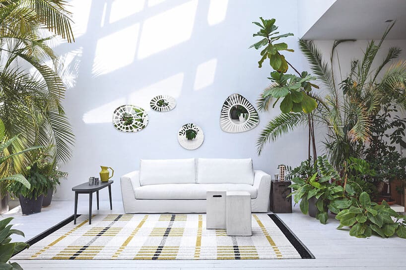 jasne wnętrze z białą sofą otoczoną wysokimi roślinami