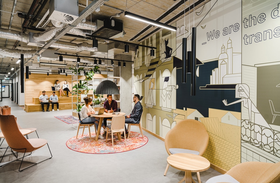 nowoczesne wnętrze open space intive troje pracowinków przy drewnianym stoliku