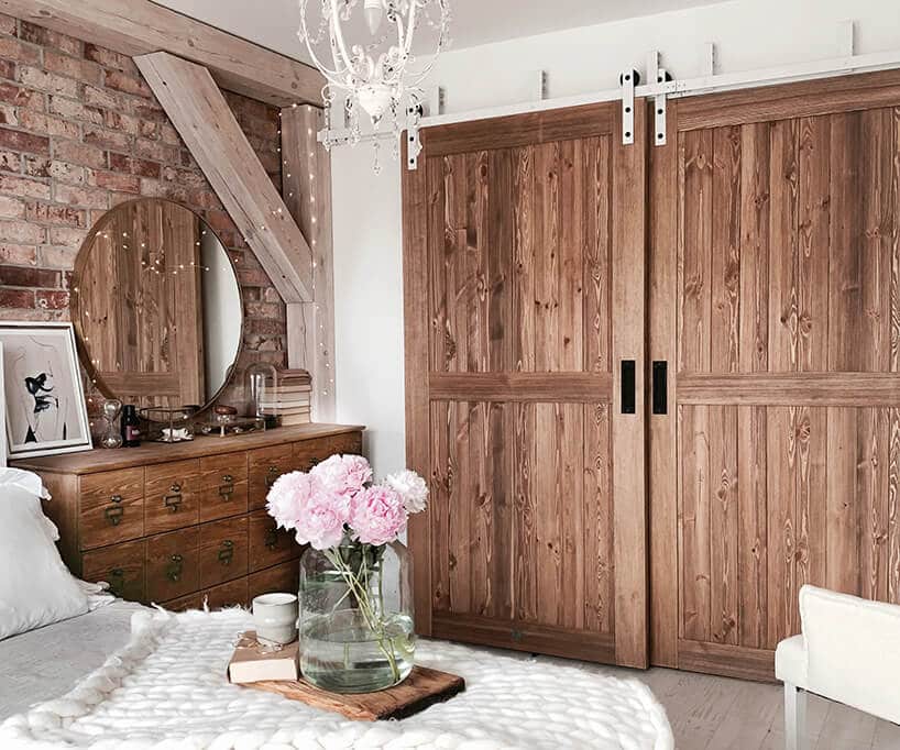 drewniane dwuskrzydłowe duże drzwi przesuwne w sypialni z drewnianymi belkami narożnymi