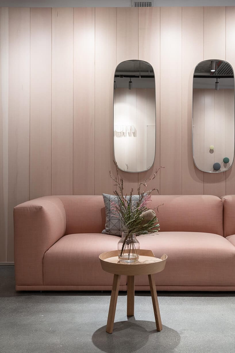 jasno różowa sofa pod dwoma lustrami zaokrąglonymi lustrami
