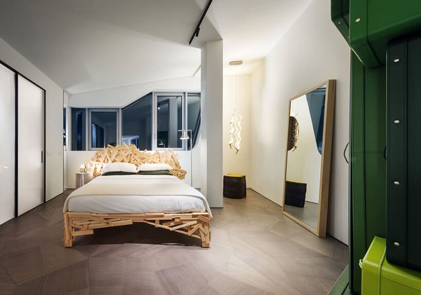 elegancki penthouse od Zaha Hadid biała sypialnia z duzym łóżkiem wykończonym małymi deseczkami o różnych wielkościach