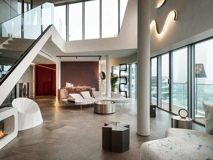 elegancki penthouse od Zaha Hadid widok na salon i antresolę ze schodami ze szklaną balustradą