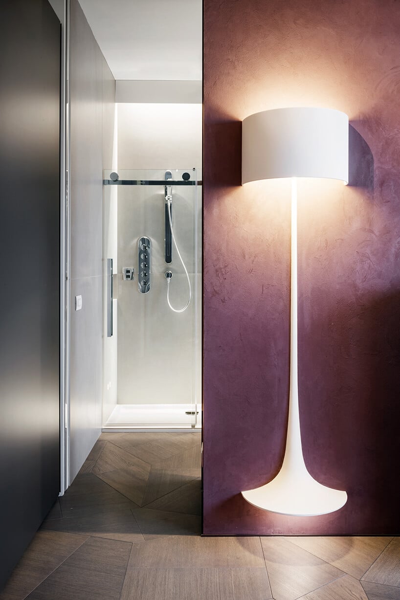 elegancki penthouse od Zaha Hadid wyjątkowa łazienka z fioletową ścianą i zamontowaną na nią lampą ze świecącą podstawką