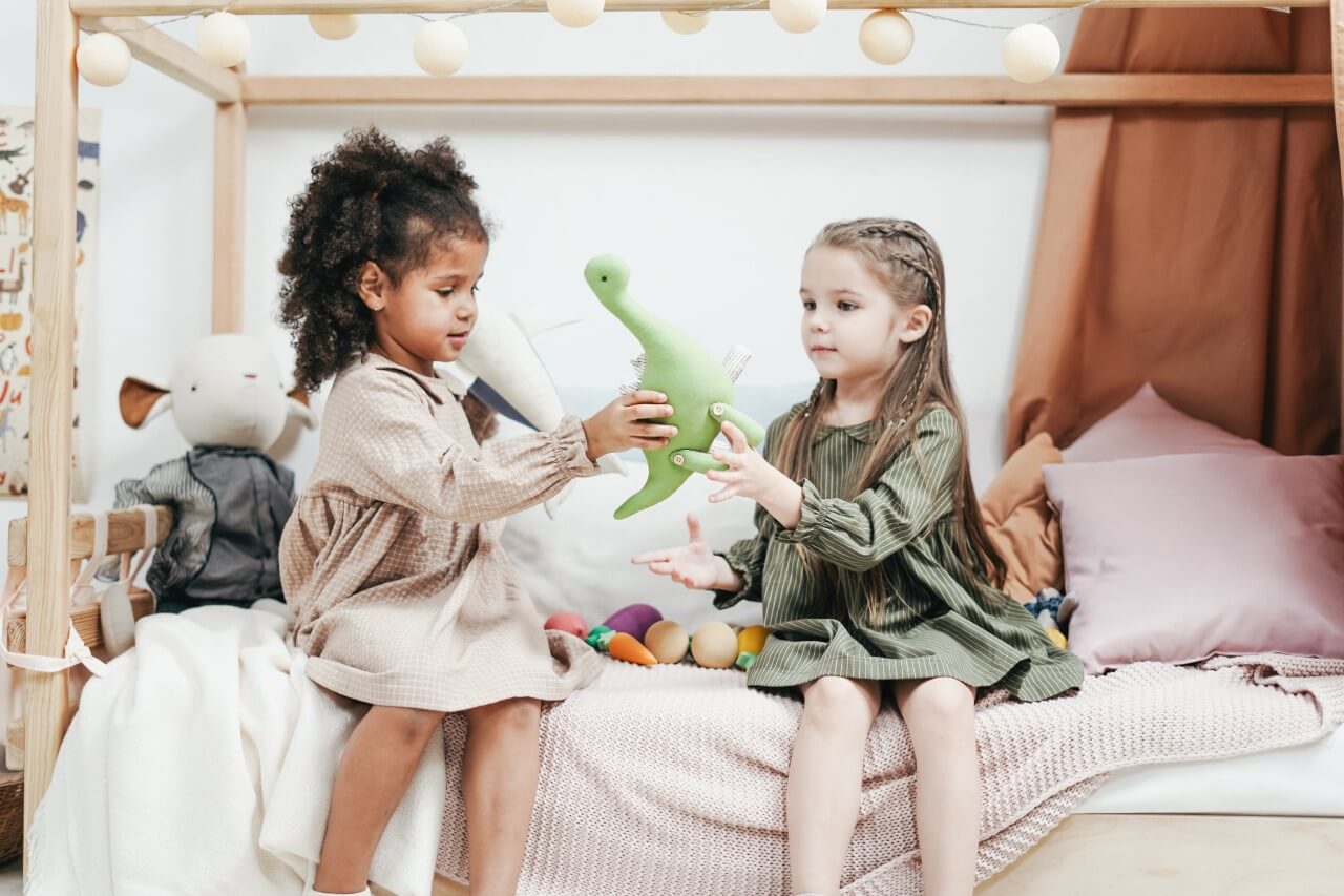dziewczynki bawiące się dinozaurami w różowej sypialni