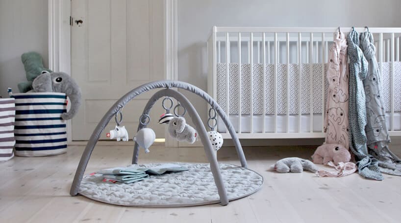 biały pokój dla niemowlaka z drewnianym łóżeczkiem i szarą matą edukacyjną dla niemowlaka