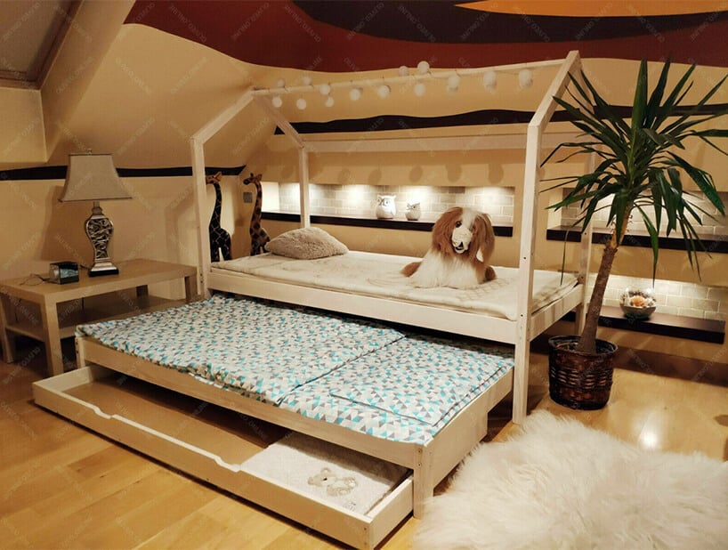 drewniane łóżko domek Bella z łańcuchem świateł na górnej belce w pokoju dziecięcym na poddaszu