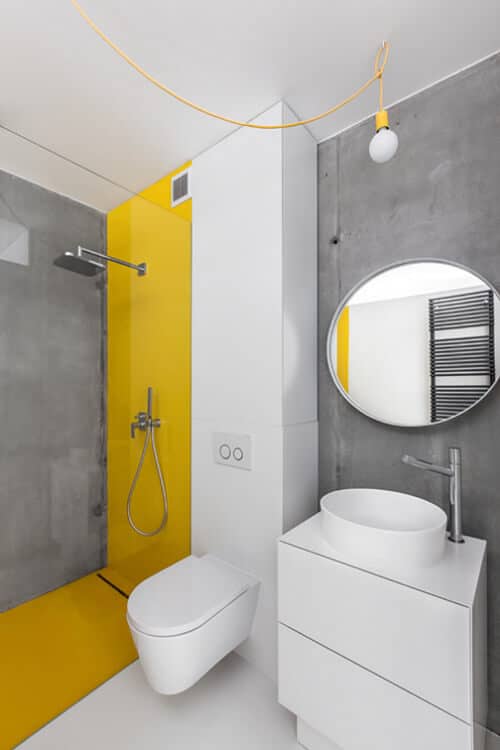 mała łazienka w szaro-białych kolorach z żółtym akcentem pod prysznicem