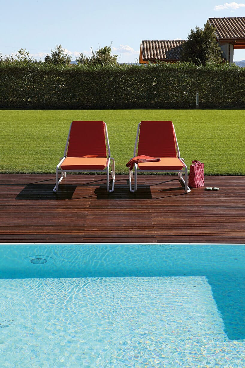 drewniany taras nad basenem z dwoma leżakami