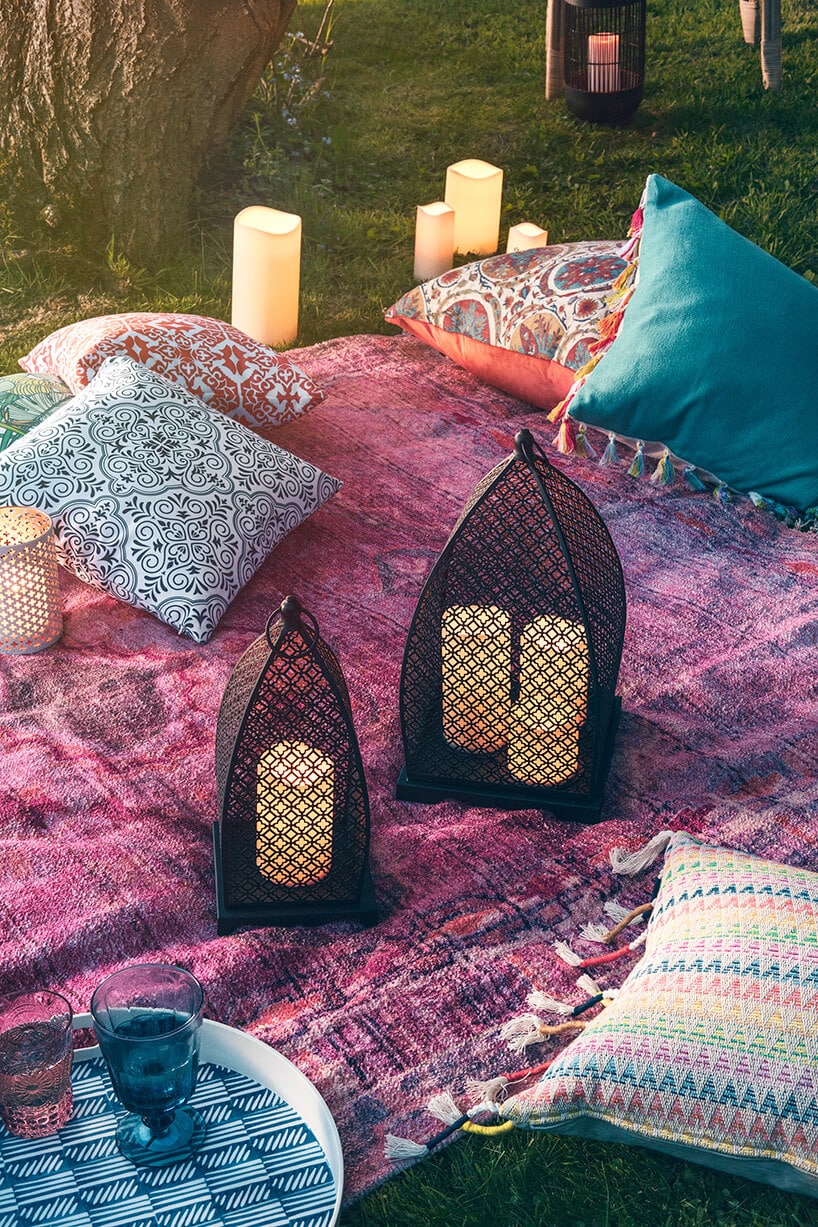 styl marokański czarne eleganckie lampiony na fioletowej narzucie z poduszkami na trawie