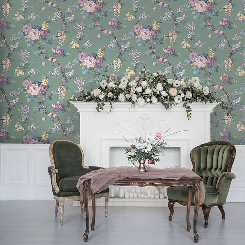 elegancki drewniany stół z dwoma klasycznymi fotelami na tle białego kominka na ścianie z motywem kwiatów Magnolii
