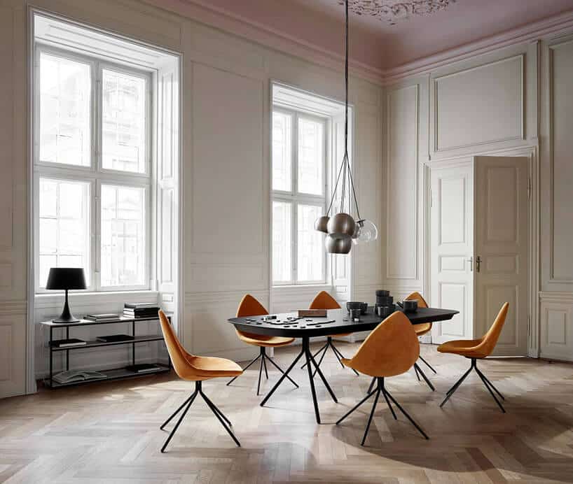 minimalistyczne wnętrze jadalni z czarnym stołem i pomarańczowymi krzesłami