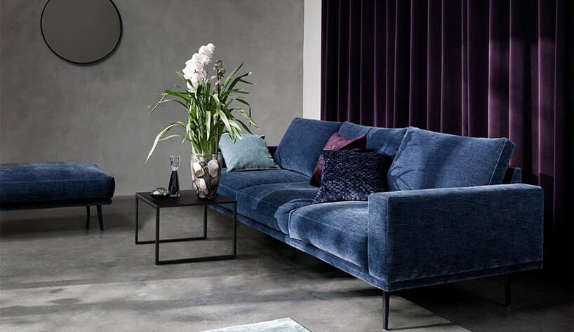 ciemno niebieska sofa na tle fioletowych zasłon