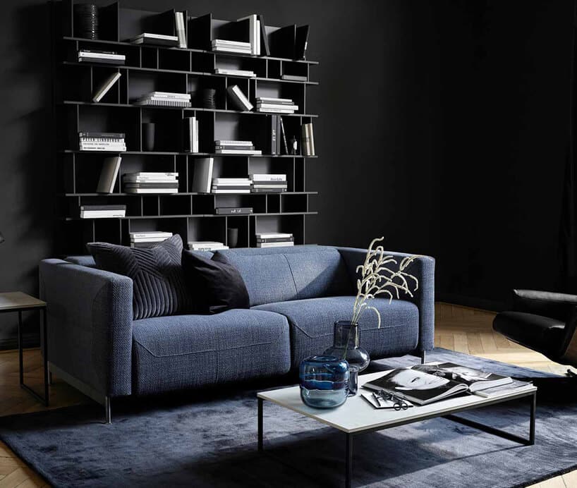 czarne wnętrze z półką z książkami i niebieską sofą